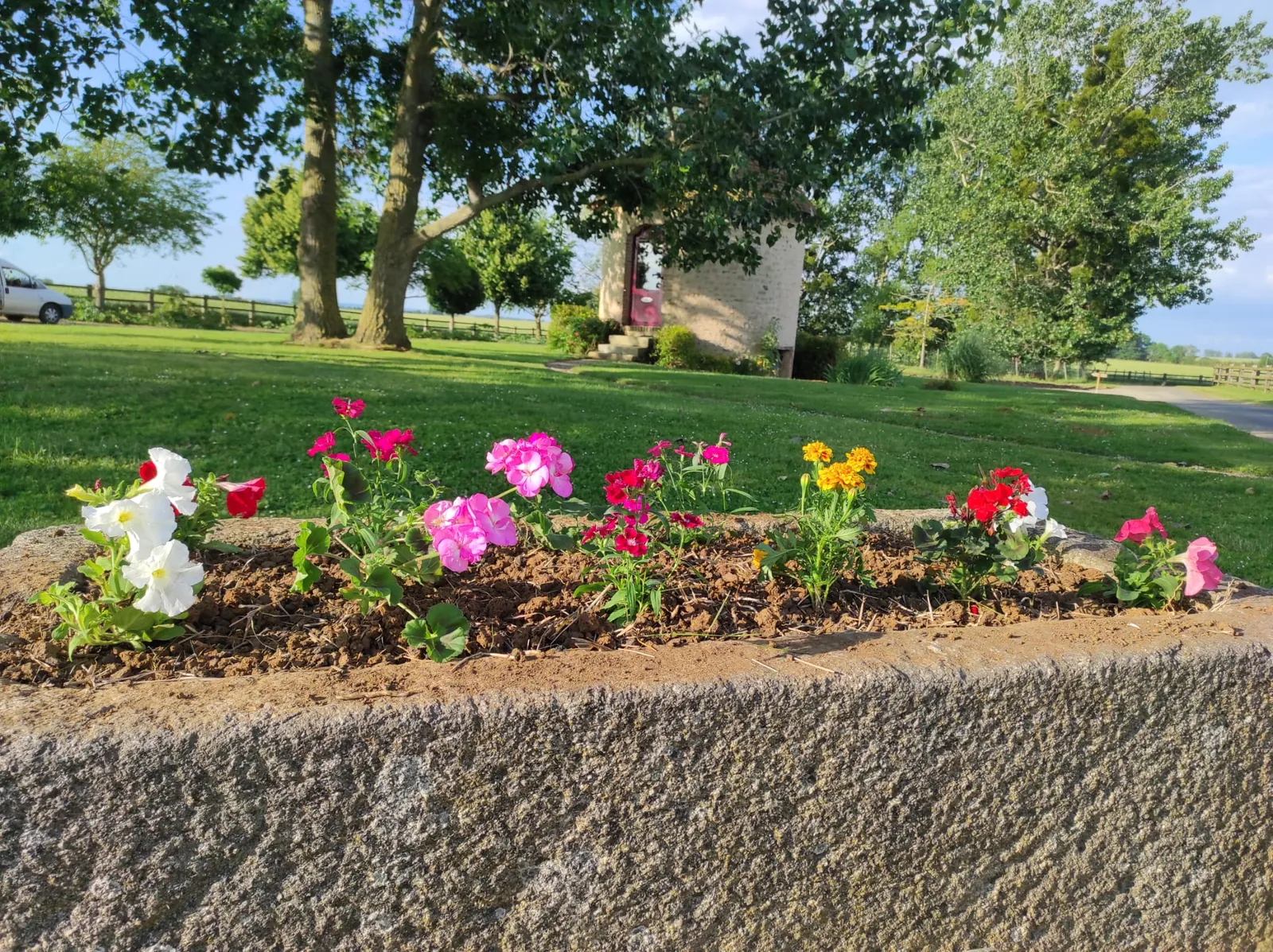 Un massif de fleurs devant le parc arboré du domaine