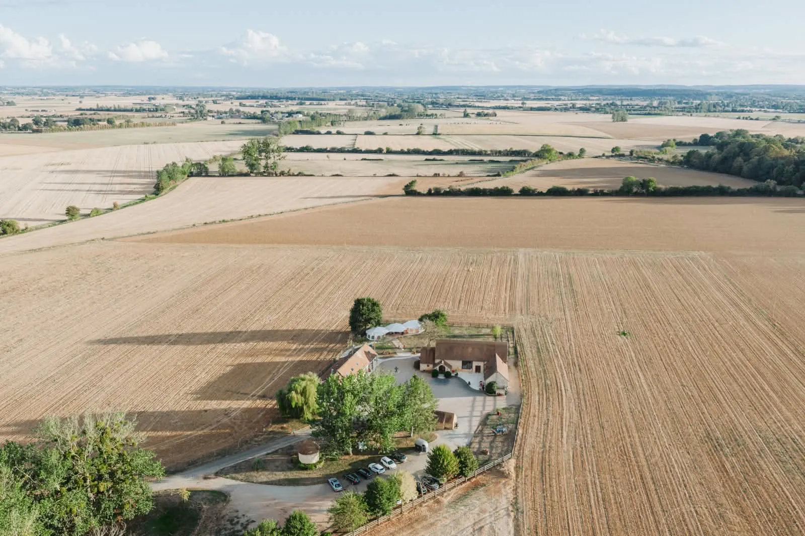 Vue aérienne du Pontaubeau : la ferme, sa cour et ses arbres au milieu des champs du Nord Sarthe
