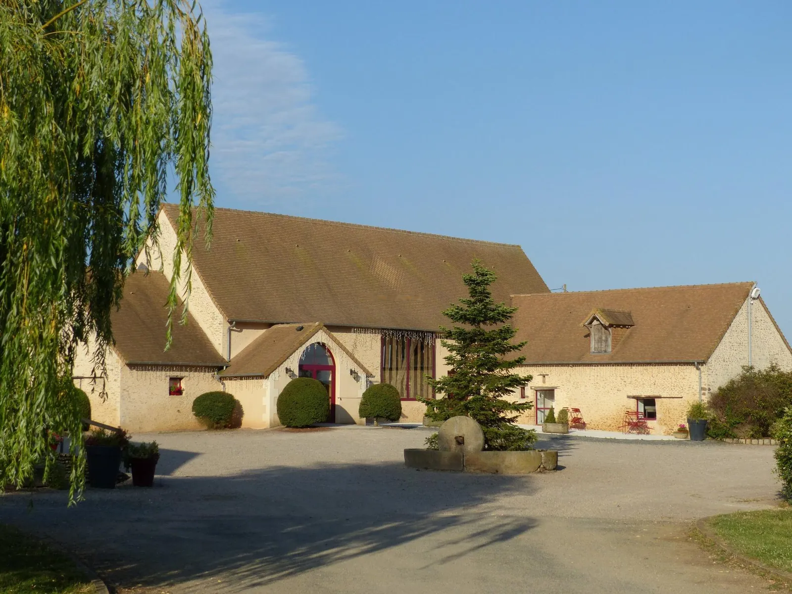 La salle de réception en pierre, le grand saule et le sapin de la cour