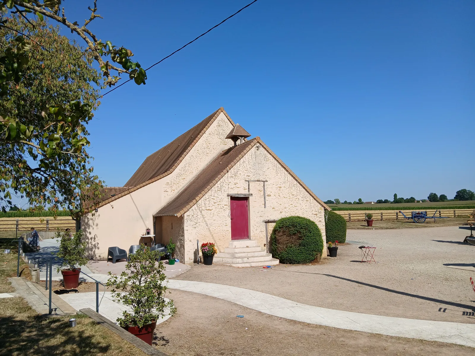 Le pignon de la salle de réception, porte rouge et perron, en plein été