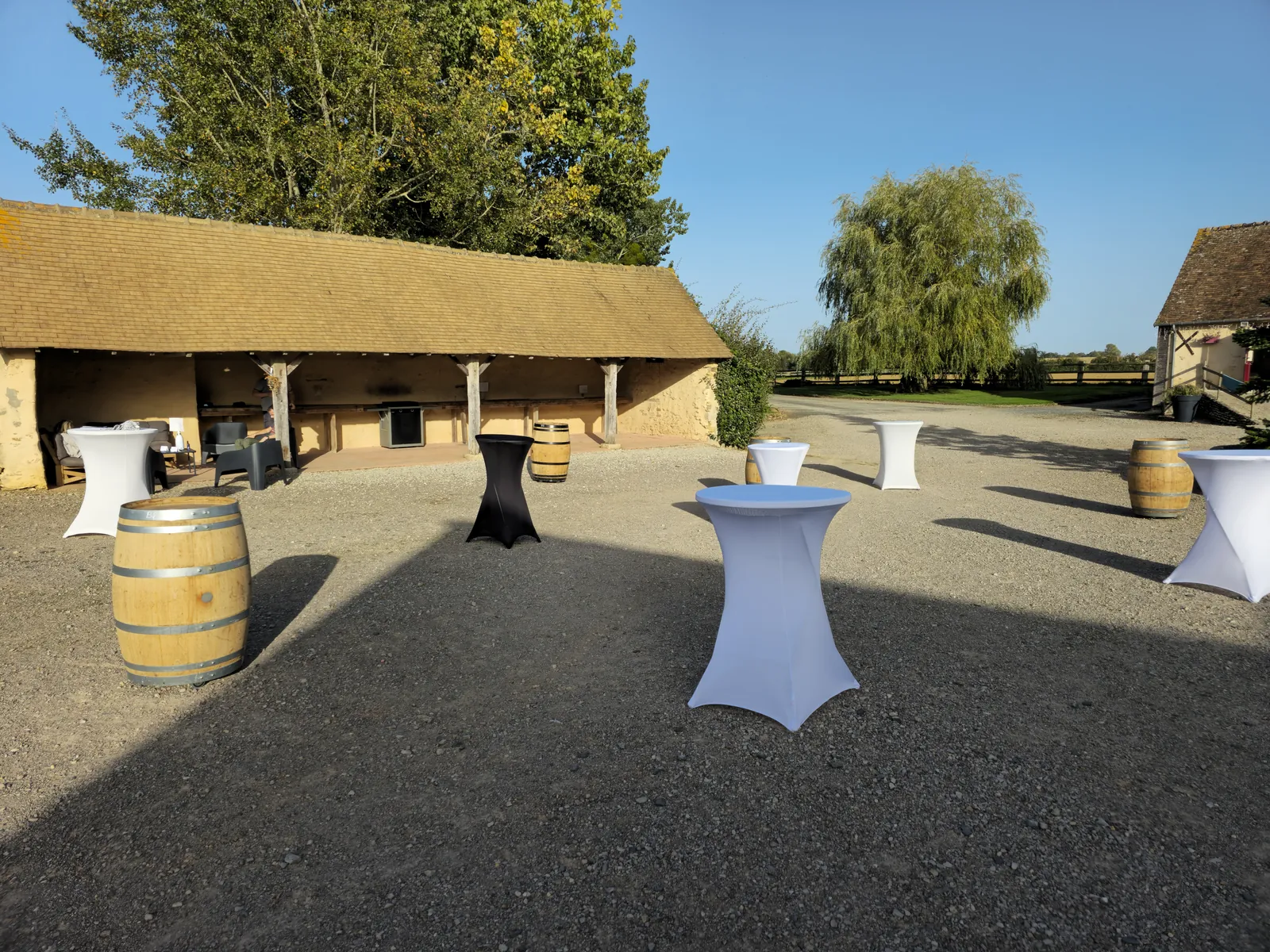 La cour préparée pour un vin d’honneur : mange-debout et tonneaux à l’ombre