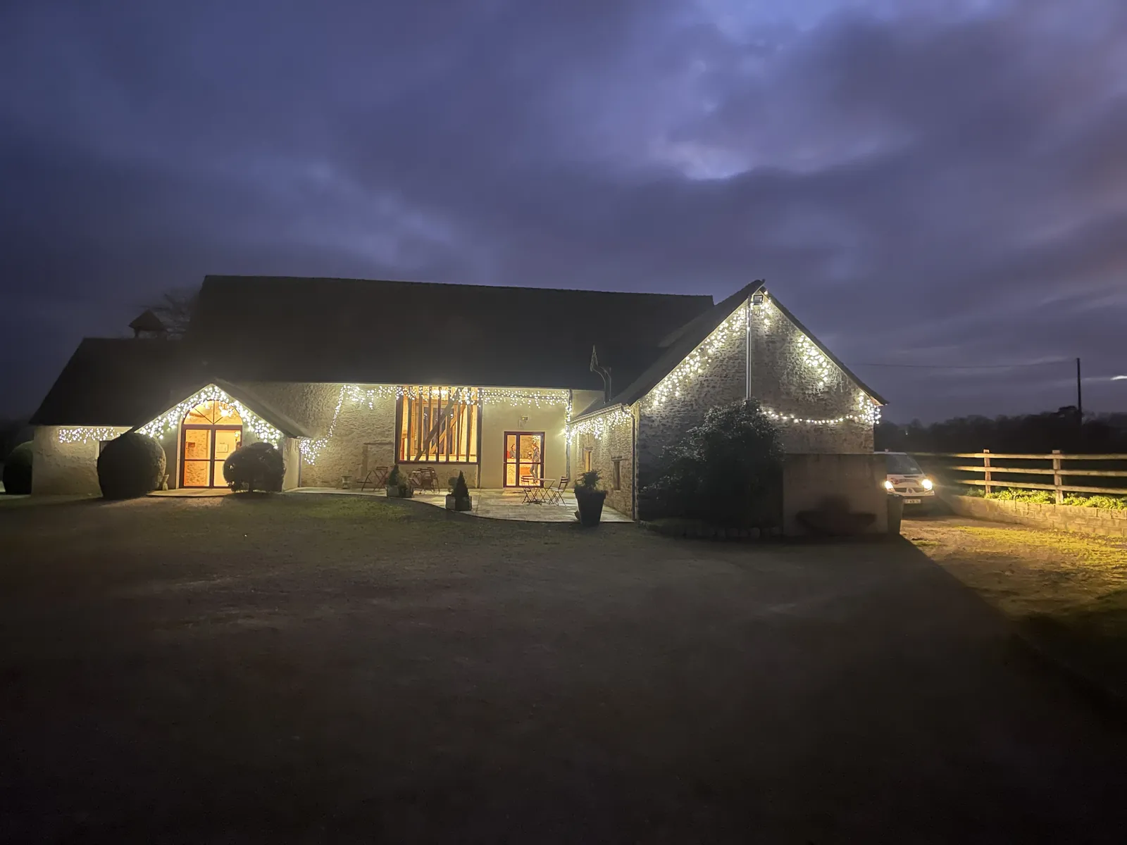 La salle de réception illuminée de guirlandes à la tombée de la nuit