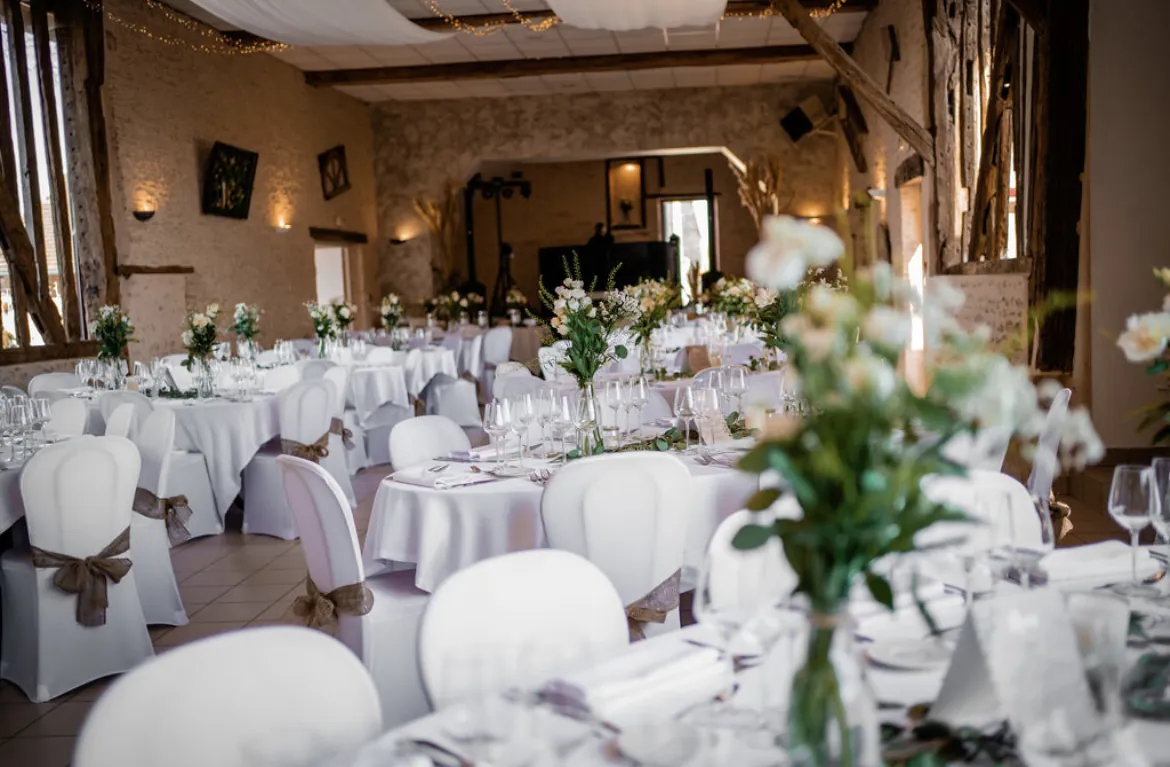 Tables rondes et housses blanches sous les colombages de la salle
