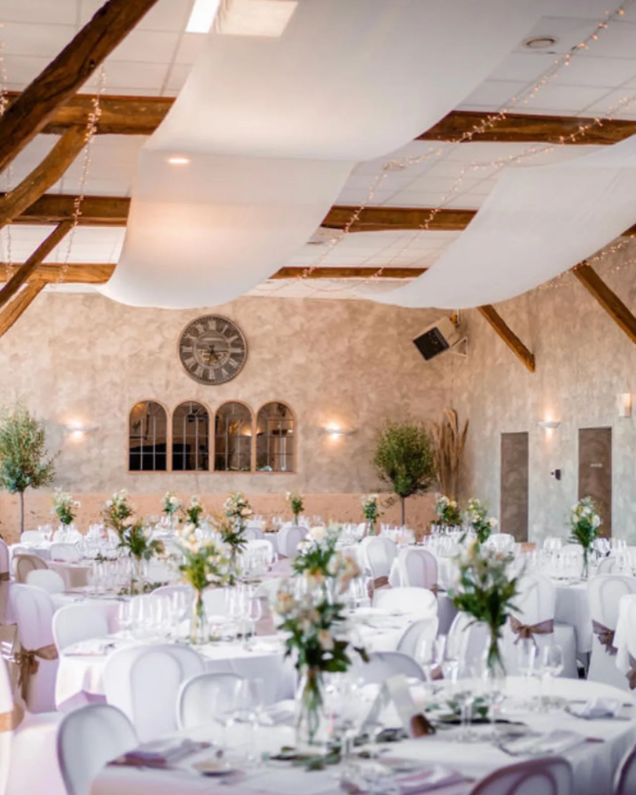 Plafond drapé de voilages et tables rondes fleuries
