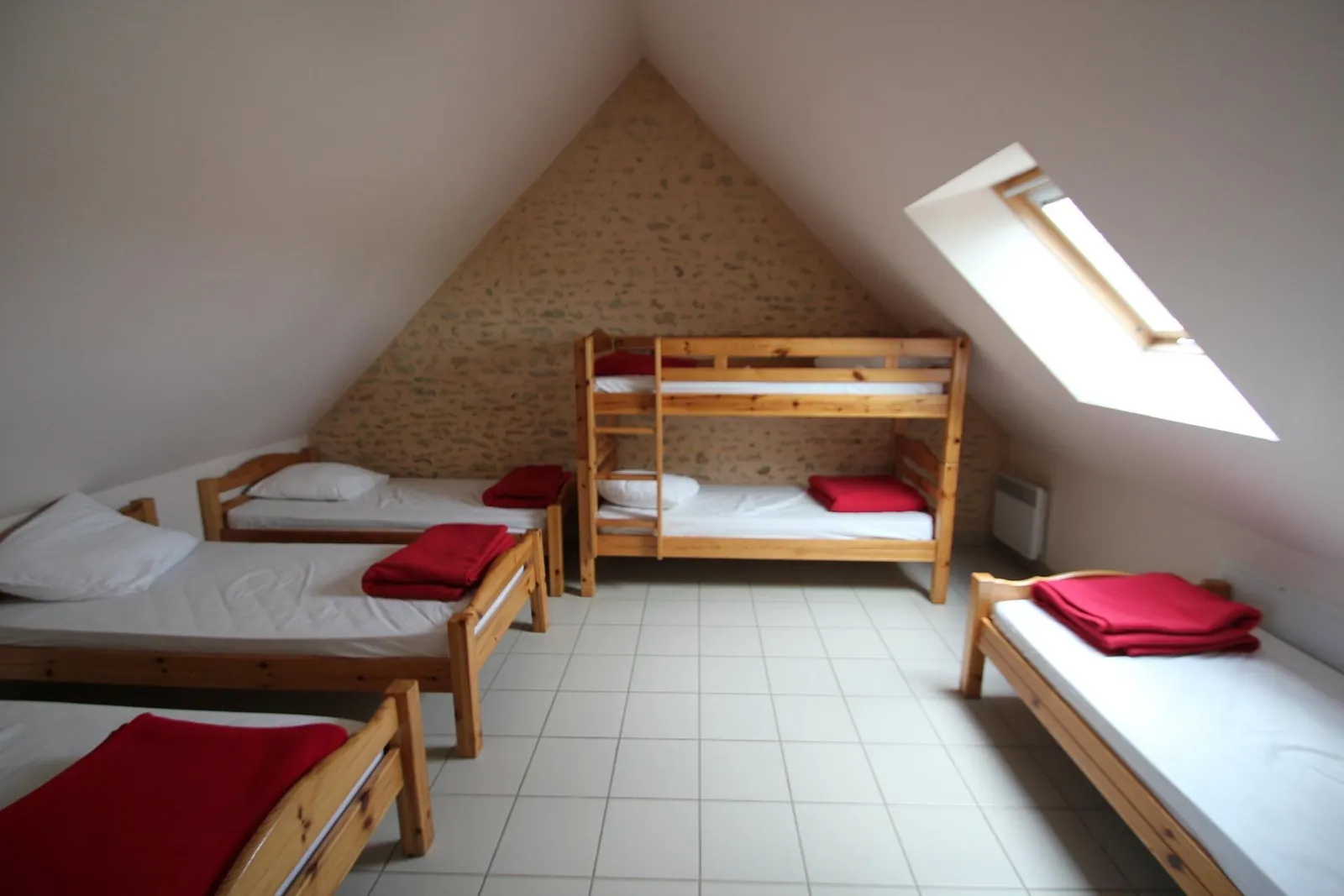 Dortoir sous les combles du gîte : lits simples et lits superposés