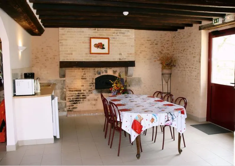 La salle des petits-déjeuners : grande table et cheminée en pierre